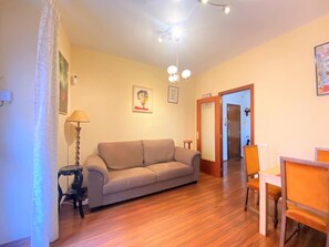 Un salon comprenant un canapé, une table à manger avec des chaises, une lampe et un luminaire au plafond.