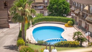 A residential area with a swimming pool surrounded by greenery and a multi-story building. - House in La Mora - 8 guests (Tarragona)