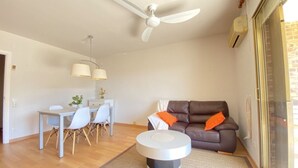 A modern living room with a brown leather sofa, a round coffee table, a dining area with a white table and chairs, and a ceiling fan. - House in La Mora - 8 guests (Tarragona)
