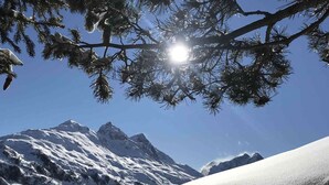 Un paisaje montañoso nevado con cielos despejados y luz solar.