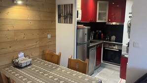 Una cocina compacta con electrodomésticos modernos, una mesa de comedor con mantel estampado y sillas de madera.