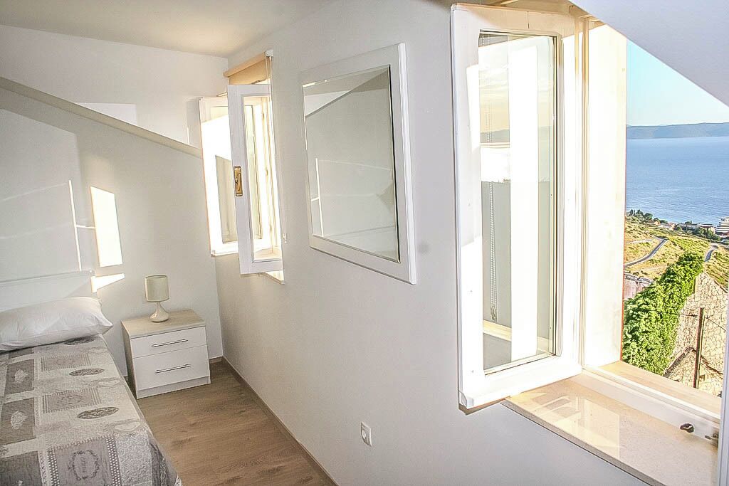 Une chambre à coucher avec un lit, une table de chevet et une fenêtre donnant sur la mer.