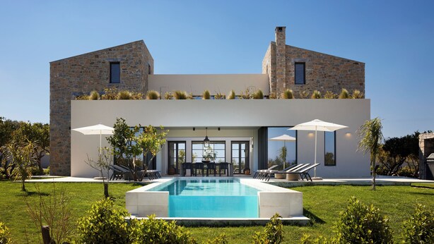 Une maison moderne dotée d’une piscine, de murs en pierre et d’un espace salon extérieur.