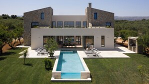 Une maison moderne à deux étages, dotée d’une piscine, d’un espace extérieur aménagé et offrant une vue sur la campagne.