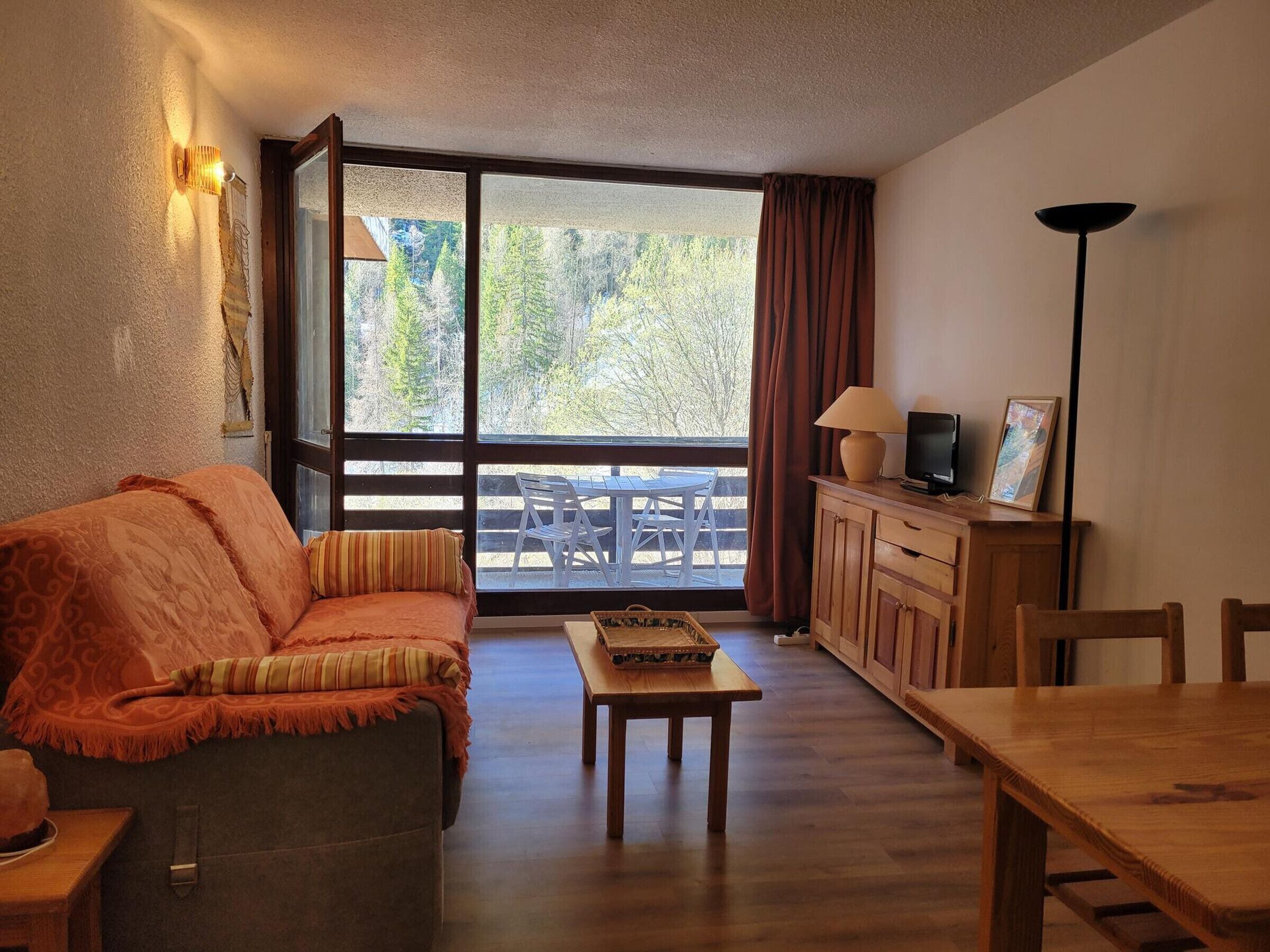 A cozy living room with a sofa, a coffee table, a TV, and a wooden cabinet.