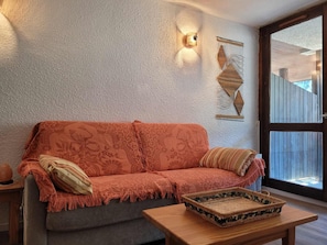 A cozy room with a sofa, a wooden table, and a woven basket. - Studio mountain view - 4 guests (Pra-Loup)