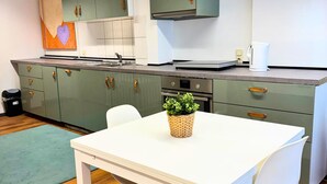 A modern kitchen with green cabinets, a white table, and a potted plant. - House with free public parking (Köln)
