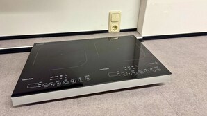 A black induction cooktop with a maximum power rating of 2100W, a power outlet, and a control panel with various cooking functions. - House with free public parking (Köln)