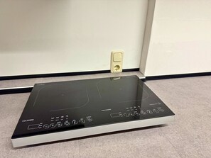 A black induction cooktop with a maximum power rating of 2100W, a power outlet, and a control panel with various cooking functions. - House with free public parking (Köln)