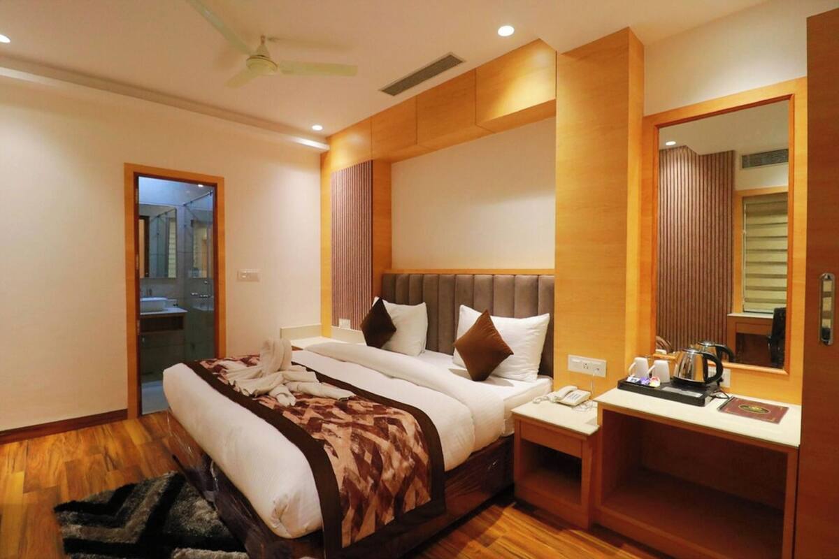 Habitación de hotel con cama, mesita de noche, espejo y vista al baño.