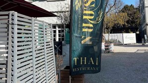 Thaimaalaisen ravintolan kyltti perinteisellä julkisivulla varustetun rakennuksen edessä.