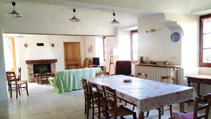A dining area with a table, chairs, a fireplace, and a clock on the wall. - LE MAS GORCE, Drôme valley, spacious TERRACE, courtyard, parking, garage. (Chabrillan)