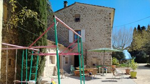 A rustic stone building with a swing set and outdoor seating area. - LE MAS GORCE, Drôme valley, spacious TERRACE, courtyard, parking, garage. (Chabrillan)