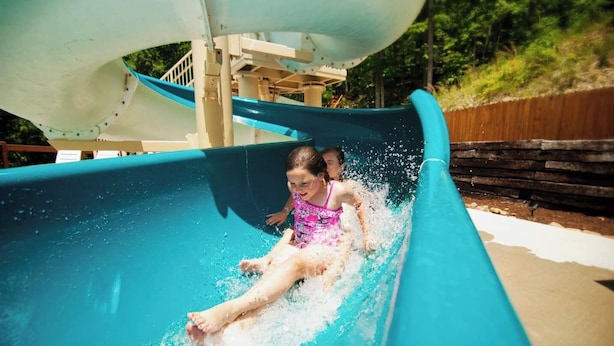 Un toboggan aquatique avec une personne au point d’arrivée, entourée d’eau.