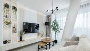 Ett modernt vardagsrum med en soffa, en tv, ett matbord och dekorativa föremål.