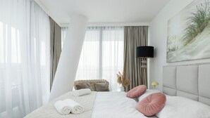 Ett hotellrum med en säng, ett nattduksbord, en lampa och en tavla på väggen.