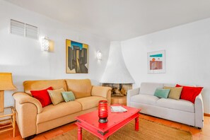 A living room with two sofas, a red coffee table, a lamp, and two wall-mounted light fixtures. - Elegant townhouse with pool in Vilamoura (Quarteira)