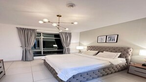 A bedroom with a large bed, a window with curtains, a bedside table, and a wall-mounted light fixture. - Adorable 1-BD apartment with very unique location in Dubai down town (Dubai)