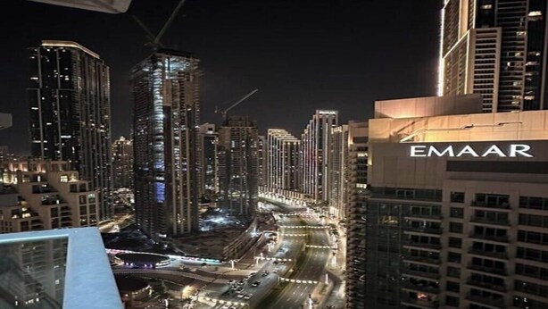 A nighttime cityscape with high-rise buildings, including a prominent EMAAR building. - Adorable 1-BD apartment with very unique location in Dubai down town (Dubai)