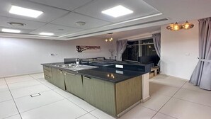 A modern kitchen with a central island, recessed ceiling lights, and a dining area with a sofa. - Adorable 1-BD apartment with very unique location in Dubai down town (Dubai)