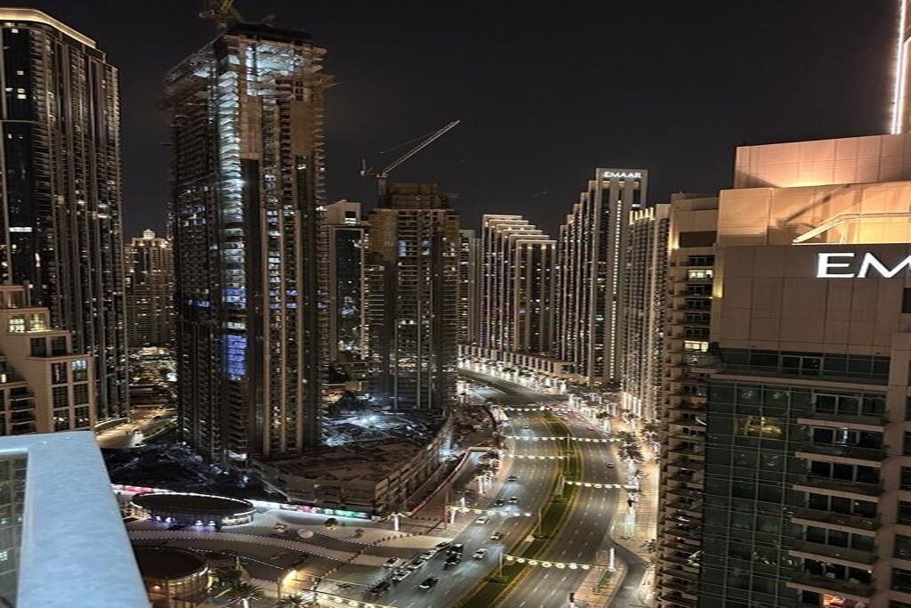 A high-rise urban area with modern buildings, a curved road, and a prominent building with 'EM' signage.
