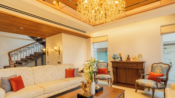 Uma sala de estar ampla com sofá, poltronas, mesa de centro e lareira.