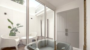 A modern room with a glass table, two chairs, a potted plant, and a large wardrobe. - GRA A Terrace by Homing (Lisbon)
