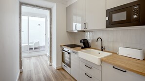 A modern kitchen with a microwave, toaster, sink, and oven. - GRA A Terrace by Homing (Lisbon)