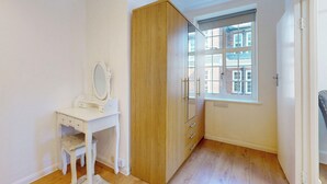 Una stanza con una toeletta bianca, un'armadio in legno e una finestra che si affaccia su edifici.