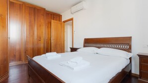 A hotel room with a wooden bed, a wardrobe, and a nightstand. - Cozy 50m2 apartment, perfect for 4 people, located on the 5th floor of a building with lift just 500m from Parco Nord, the largest green area in Milan!At 500m there is the Bruzzano-Parco Nord stop of the S2/S4 suburban train which in just a few stops t (Milan)