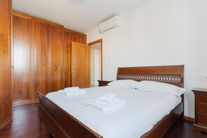 A hotel room with a wooden bed, a wardrobe, and a nightstand. - Cozy 50m2 apartment, perfect for 4 people, located on the 5th floor of a building with lift just 500m from Parco Nord, the largest green area in Milan!At 500m there is the Bruzzano-Parco Nord stop of the S2/S4 suburban train which in just a few stops t (Milan)