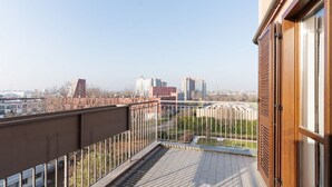 A balcony with a metal railing, a wooden door, and a view of buildings and greenery. - Cozy 50m2 apartment, perfect for 4 people, located on the 5th floor of a building with lift just 500m from Parco Nord, the largest green area in Milan!At 500m there is the Bruzzano-Parco Nord stop of the S2/S4 suburban train which in just a few stops t (Milan)