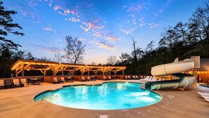 Ein Swimmingpool mit Rutsche, umgeben von einer Holzterrasse und Liegestühlen.
