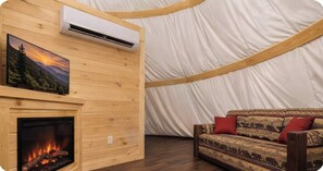 Ein Zimmer mit Kamin, einer Wandklimaanlage und einem gemusterten Sofa.