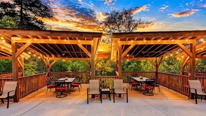 Eine Terrasse im Freien mit Holzbalkonen, Lichterketten und Tischen und Stühlen.