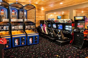 Eine Reihe von Spielautomaten, darunter NBA und Daytona USA, mit einer Holzbalkendecke und einem gemusterten Teppich.