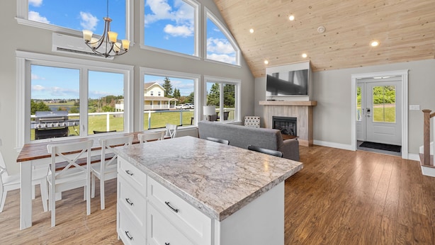 A spacious kitchen with a large island, a dining area, and a TV.