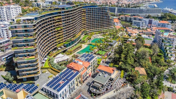 A modern hotel with a curved facade, multiple balconies, a rooftop pool, and solar panels. - Imperatriz 3F by Homie (Funchal)