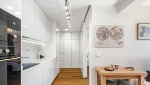 A modern kitchen with white cabinetry, a wooden dining table, and a world map on the wall. - Imperatriz 3F by Homie (Funchal)