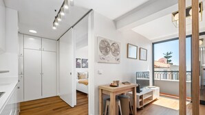 A modern, well-lit room with a bed, a desk, and a large window offering a view of the outside. - Imperatriz 3F by Homie (Funchal)
