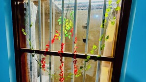 A window with metal bars, a curtain, and hanging plants. - Freedom River House (Ahangama)