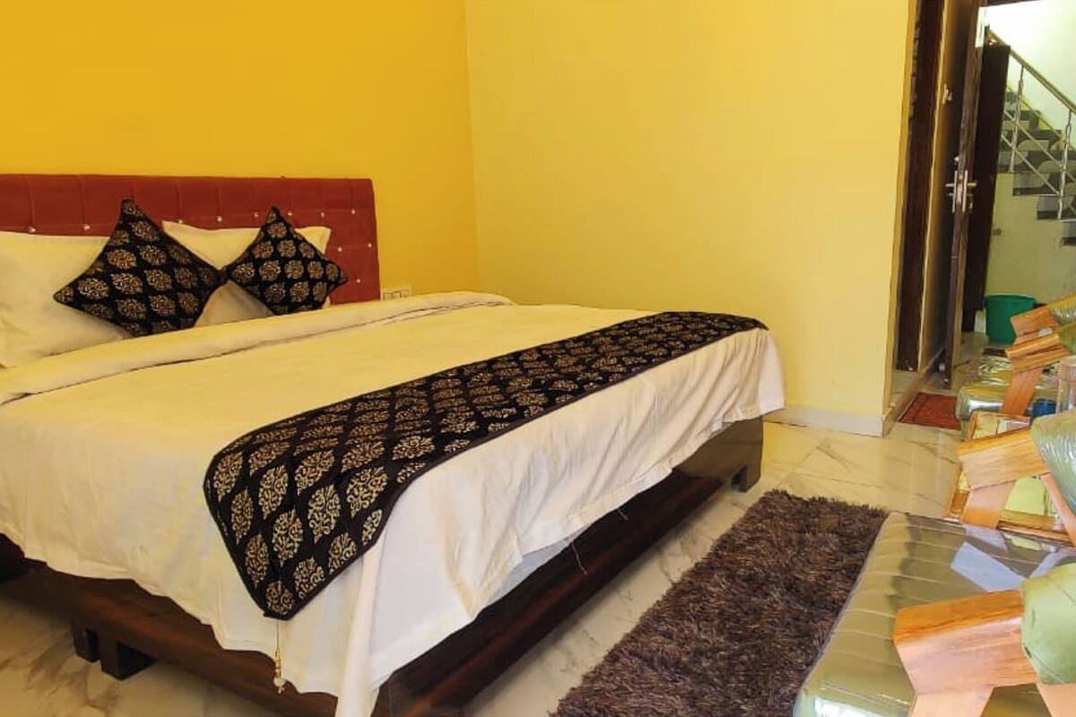 Une chambre d’hôtel avec un lit, une table de chevet, une chaise et une salle de bain visible à travers une porte ouverte.