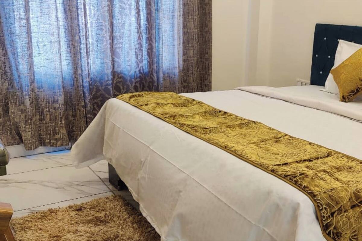 Une chambre d’hôtel avec un lit, une tête de lit et une fenêtre avec des rideaux.