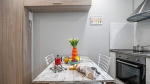 A kitchen with a wooden table, chairs, a stove, and a wall-mounted trash bin. - Italianway Easy - Buenos Aires 2 A (Milan)