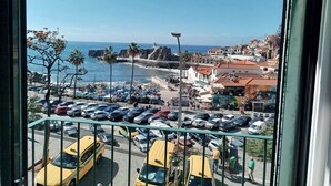 Une vue sur la côte, avec des voitures garées, une plage et des bâtiments.