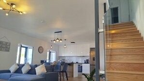Un salon moderne comprenant un canapé, un coin repas, une cuisine et un escalier.