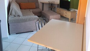 Ein Wohnzimmer mit einer Couch, einem Fernseher, einem Tisch und Kunstwerken an der Wand.