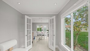 Een modern interieur met een eethoek, grote ramen en uitzicht op groen.