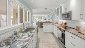 Een moderne keuken met witte kasten, granieten aanrechtbladen en een centraal eiland.