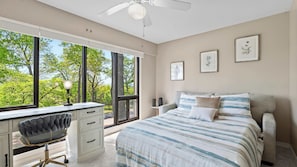 A bedroom with a bed, desk, chair, and large windows. - Lake Ozark Oasis Central Location & Pool Access (Lake Ozark)
